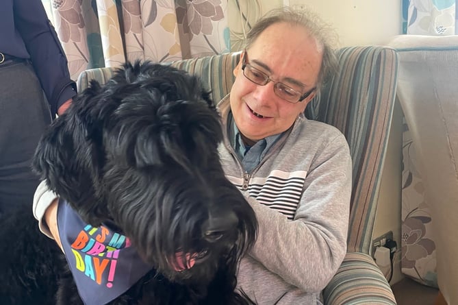 Resident Andrew Melville greets Rex, the four-legged birthday boy, at RMBI Care Co. Home Shannon Court in Hindhead.
