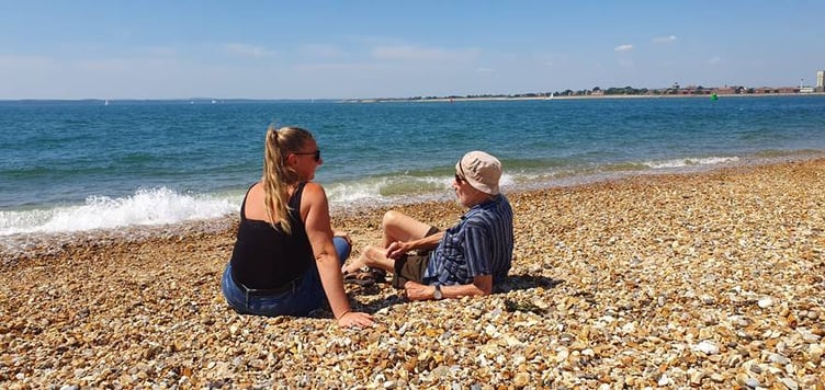 Activities co-ordinator Leah Oliver and resident Peter quietly throw pebbles while enjoying the splashing and murmuring of the waves
