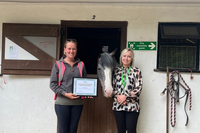 Treloar's supported internship co-ordinator Charlotte Mills presents a certificate to Broadlands Riding for the Disabled in Medstead, July 2023.