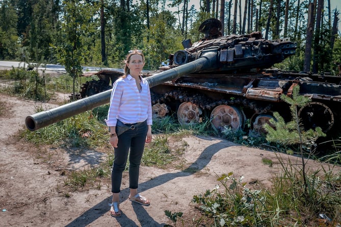 Natalia Sharomova stands in front of a burnt out tank on a recent trip back to her homeland