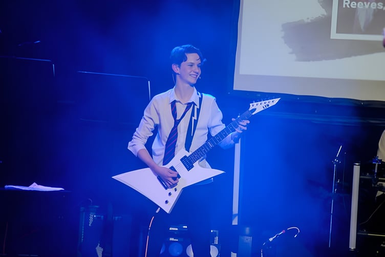 Austen performing with his guitar on stage