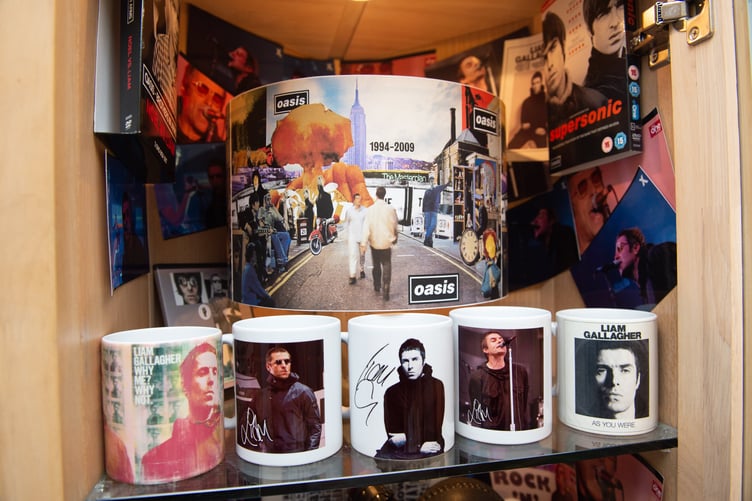 Oasis superfan John Smallbones Oasis memoribillia inside his home in Hampshire. See SWNS story SWOCoasis; Meet the Oasis superfan who has spent THOUSANDS on band memoribillia including life size cut outs of the Gallagher brothers - and his fiancee isn't even a fan. John Smallbones, 45, fell in love with the band back in 1992 and was devastated when the brothers went their separate ways. Over the past decade, window surveyor John has spent thousands of pounds on Oasis merchandise including vinyls, clothing and life size cutouts of both Gallagher brothers. He's even got Oasis tattoos and has named his business 'Wall of Glass' after the popular 2017 Liam Gallagher hit with a van plastered in stickers dedicated to the boys. His home is covered top to bottom with Oasis memorabilia, much to the amusement of his extremely patient fiancee Elaine, 46, who isn't even a fan of the band.