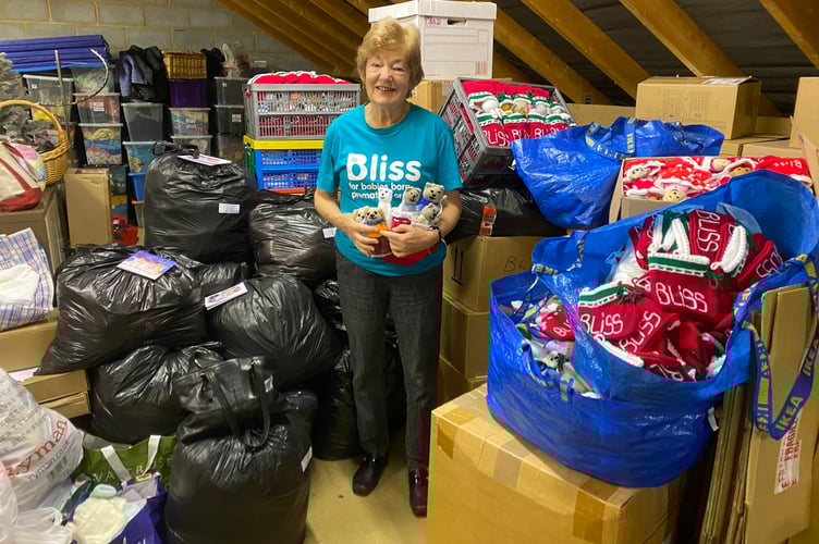 Dianne Bennett surrounded by mountains of knitted donations. 