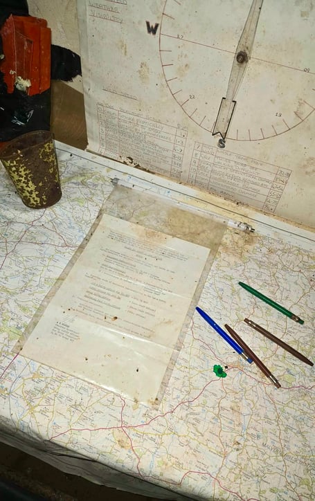 Pens and notes sit on a map in the Cold War bunker, as if the observer will return at any moment